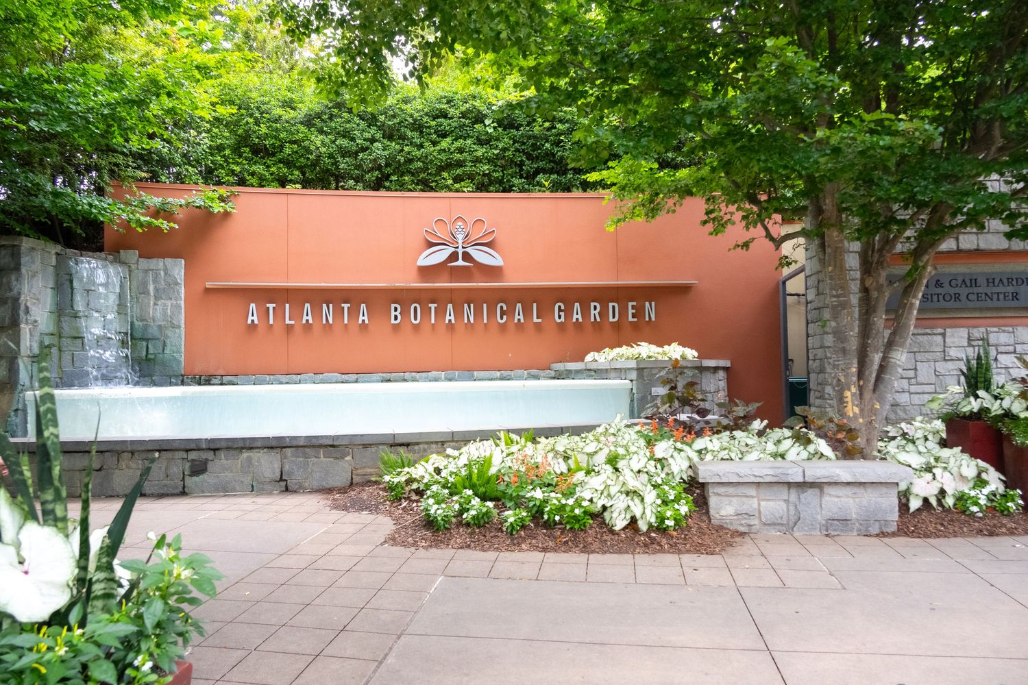 Entrance sign to Atlanta Botanical Garden with landscaped white flowers and greenery.