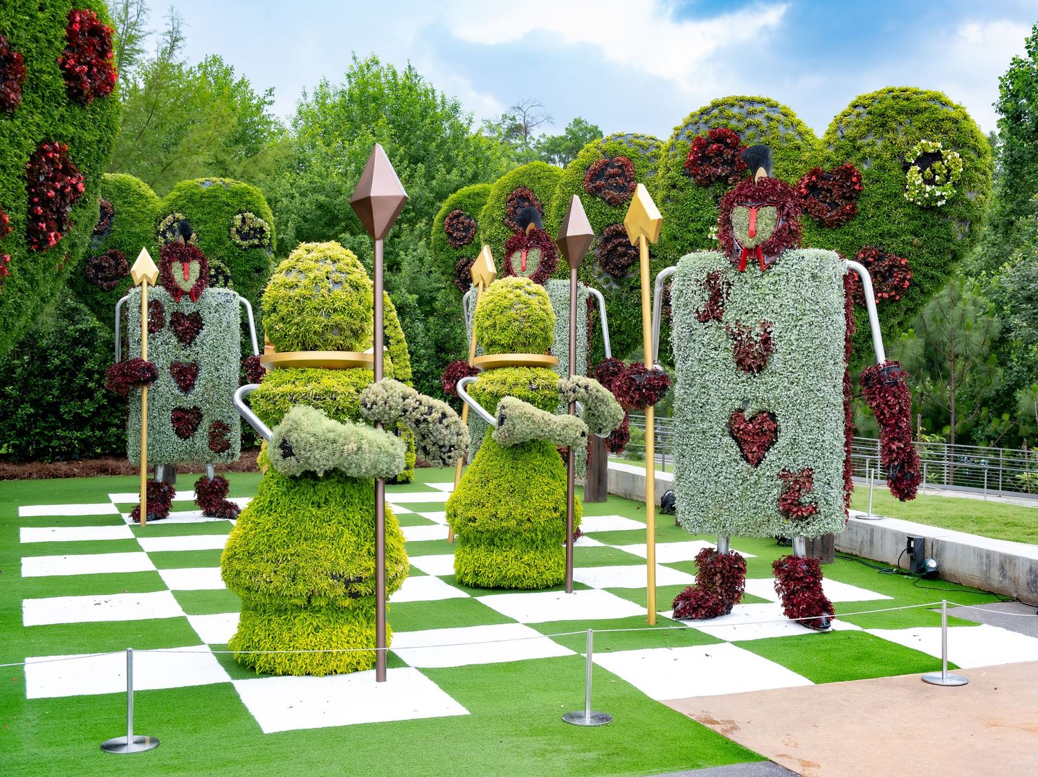 Heart-decorated topiary figures displayed on a checkerboard lawn in a decorative garden.
