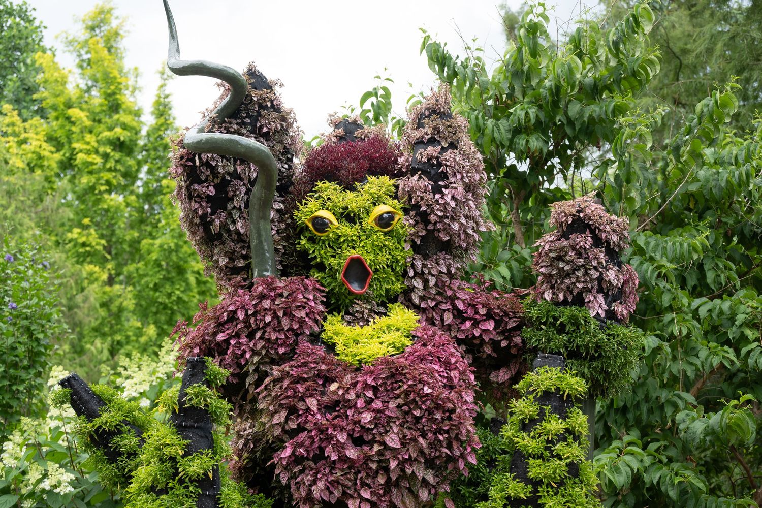 Close-up of burgundy colored flower head sculpture in garden landscape.
