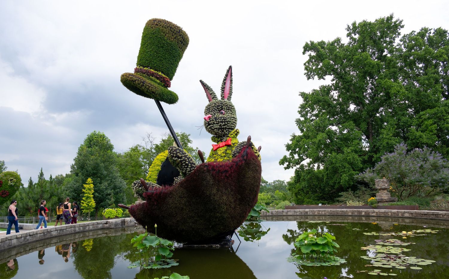 Whimsical garden sculpture featuring a topiary rabbit in boat with floating lily pads.