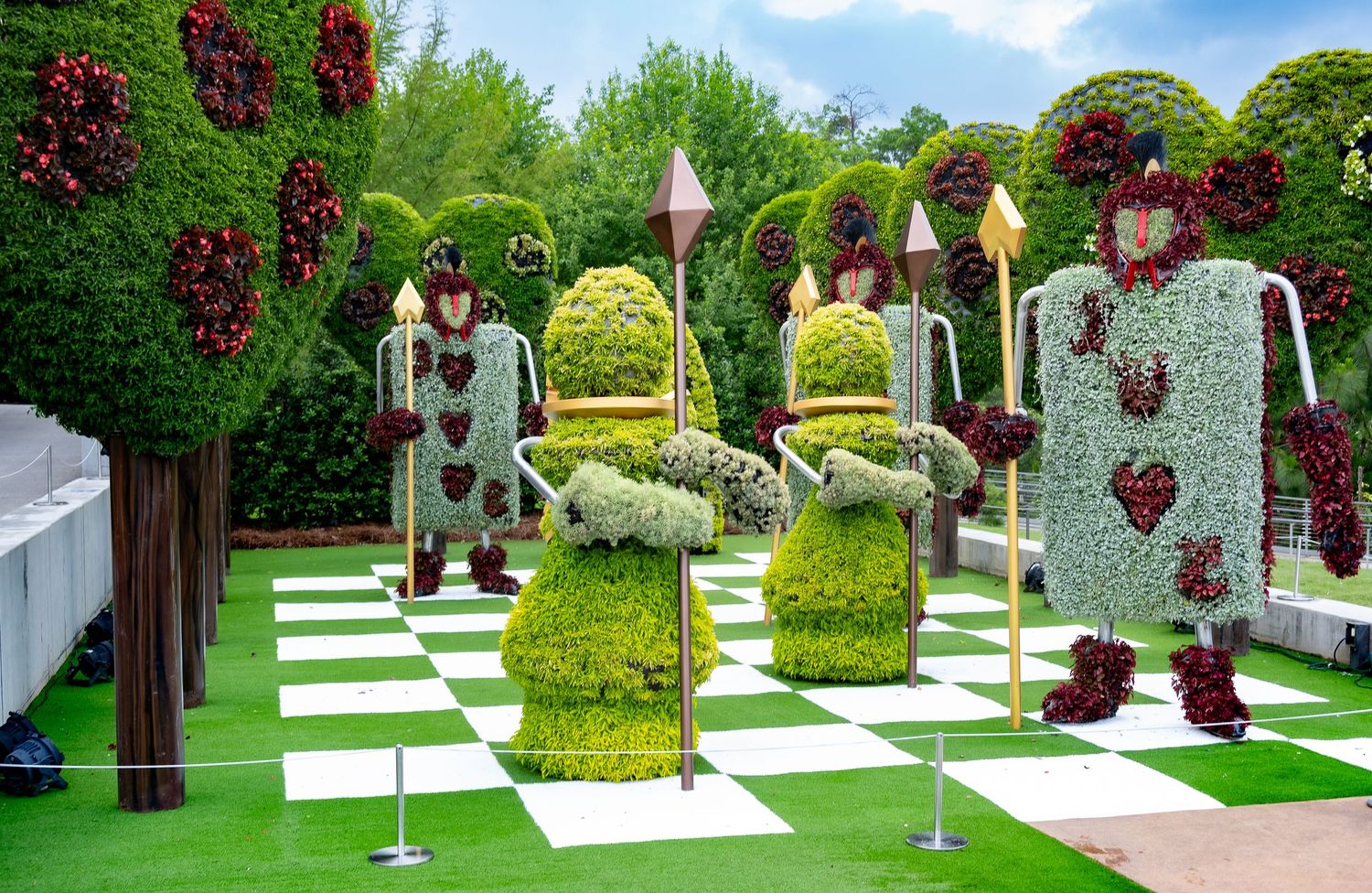 Decorative garden display with floral topiaries arranged on a checkered pathway.
