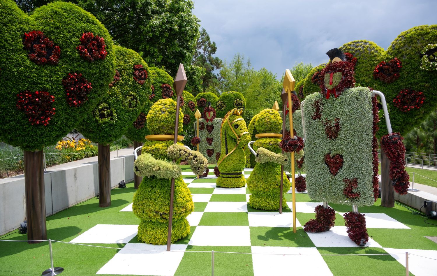 Chess-themed garden display featuring topiary figures on a green and white checkered landscape.