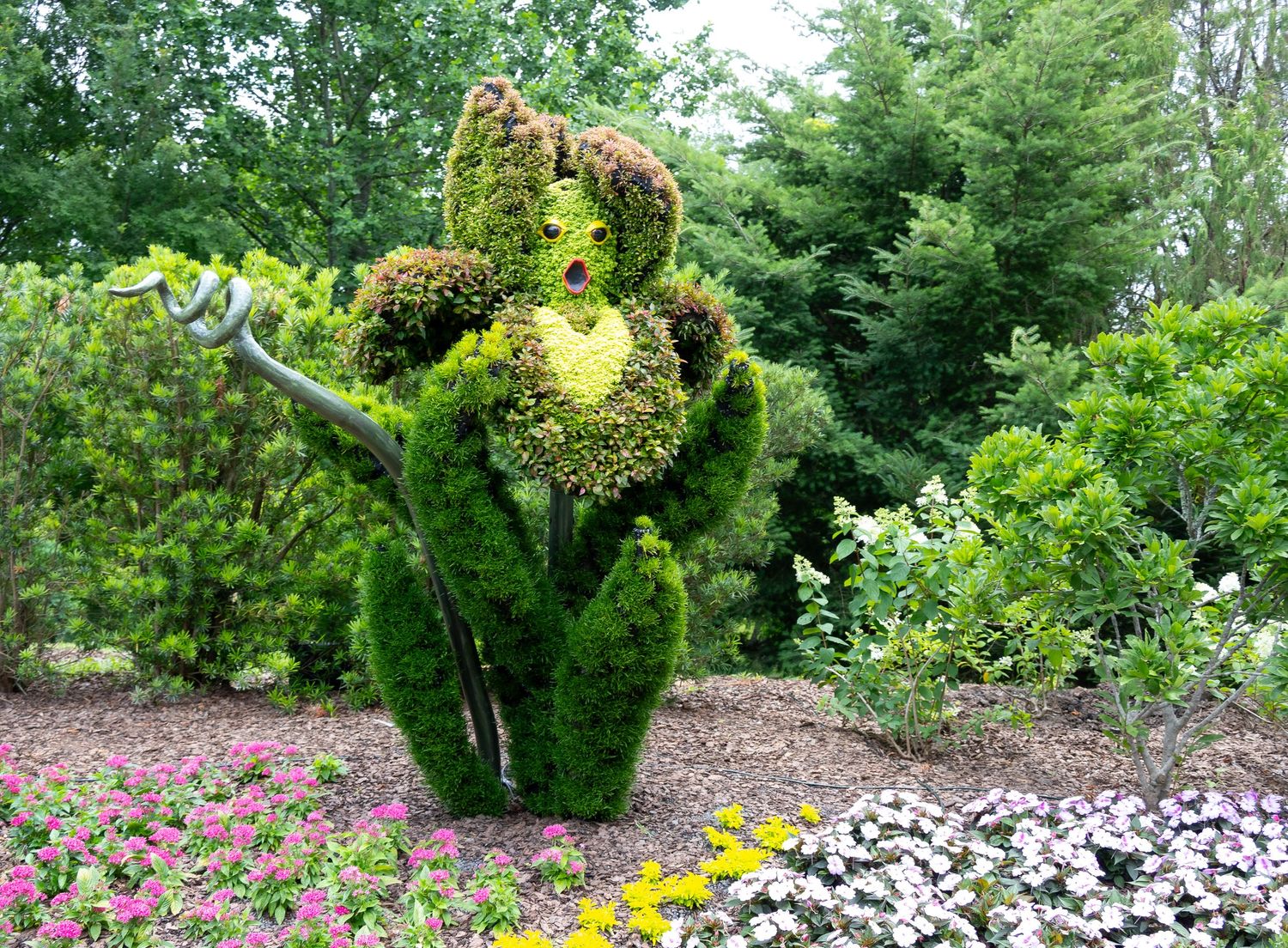 Imaginative garden sculpture created from shaped green shrubs depicting a dancing figure.