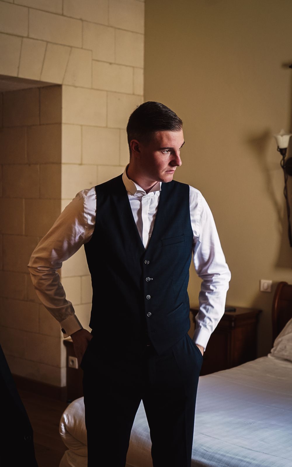 Person adjusting formal attire in a dimly lit room.