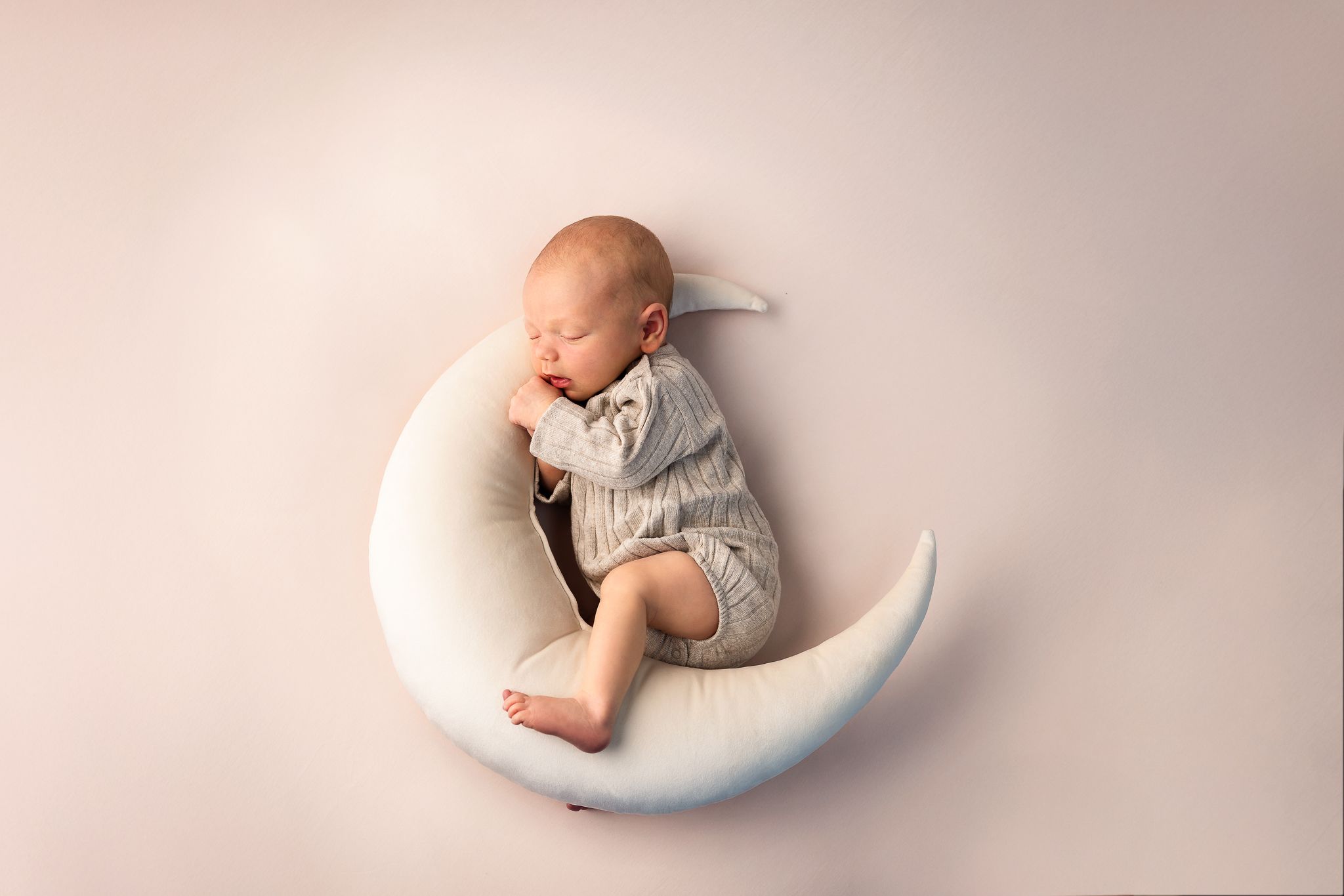A series of newborn photography poses showing a sleeping baby in white blankets on soft pink backgrounds.