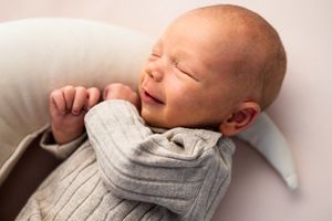 A series of photos showing a sleeping baby in a gray sweater resting on white bedding.