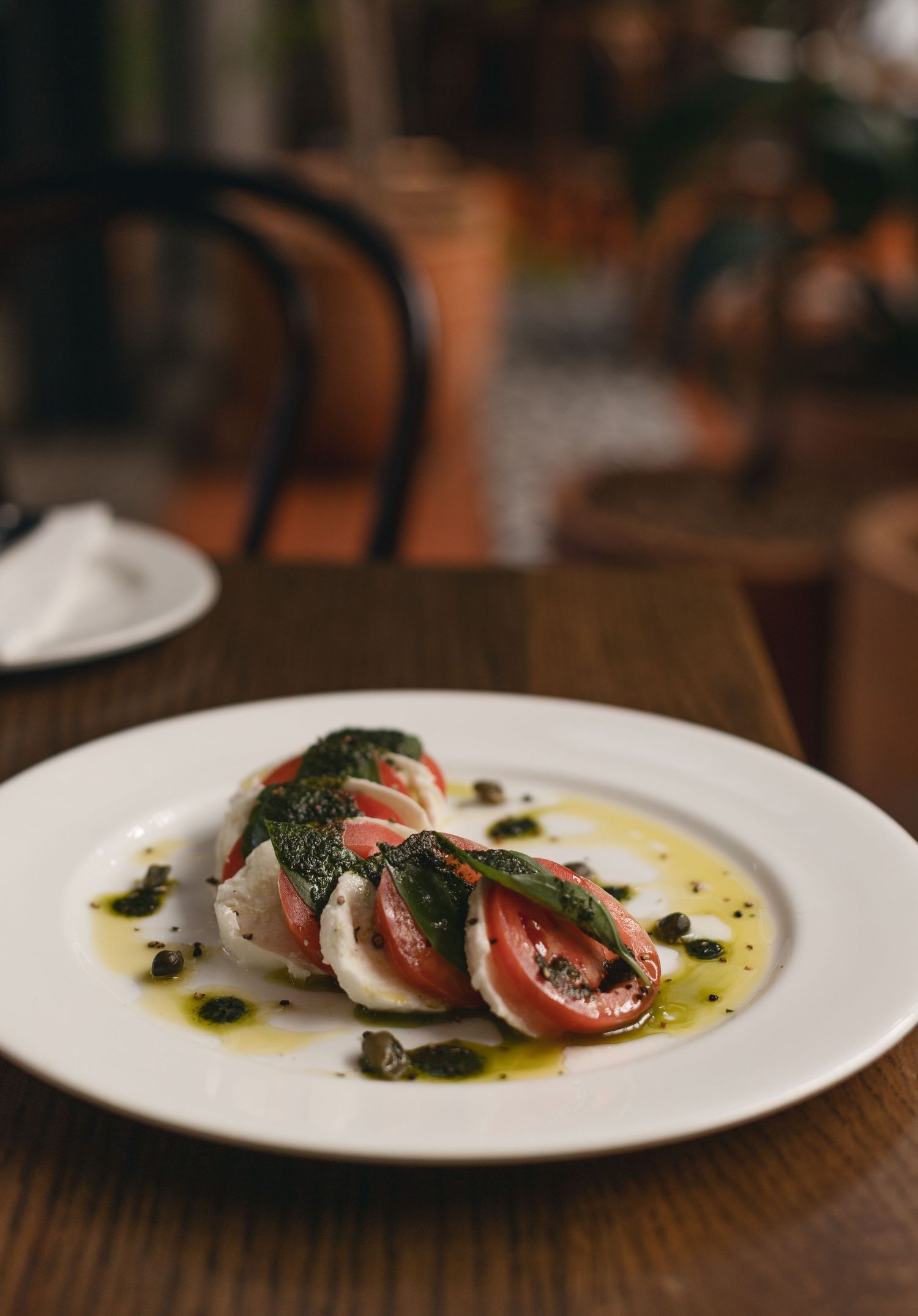 Caprese-style dish with fresh basil and olive oil drizzle on white plate.