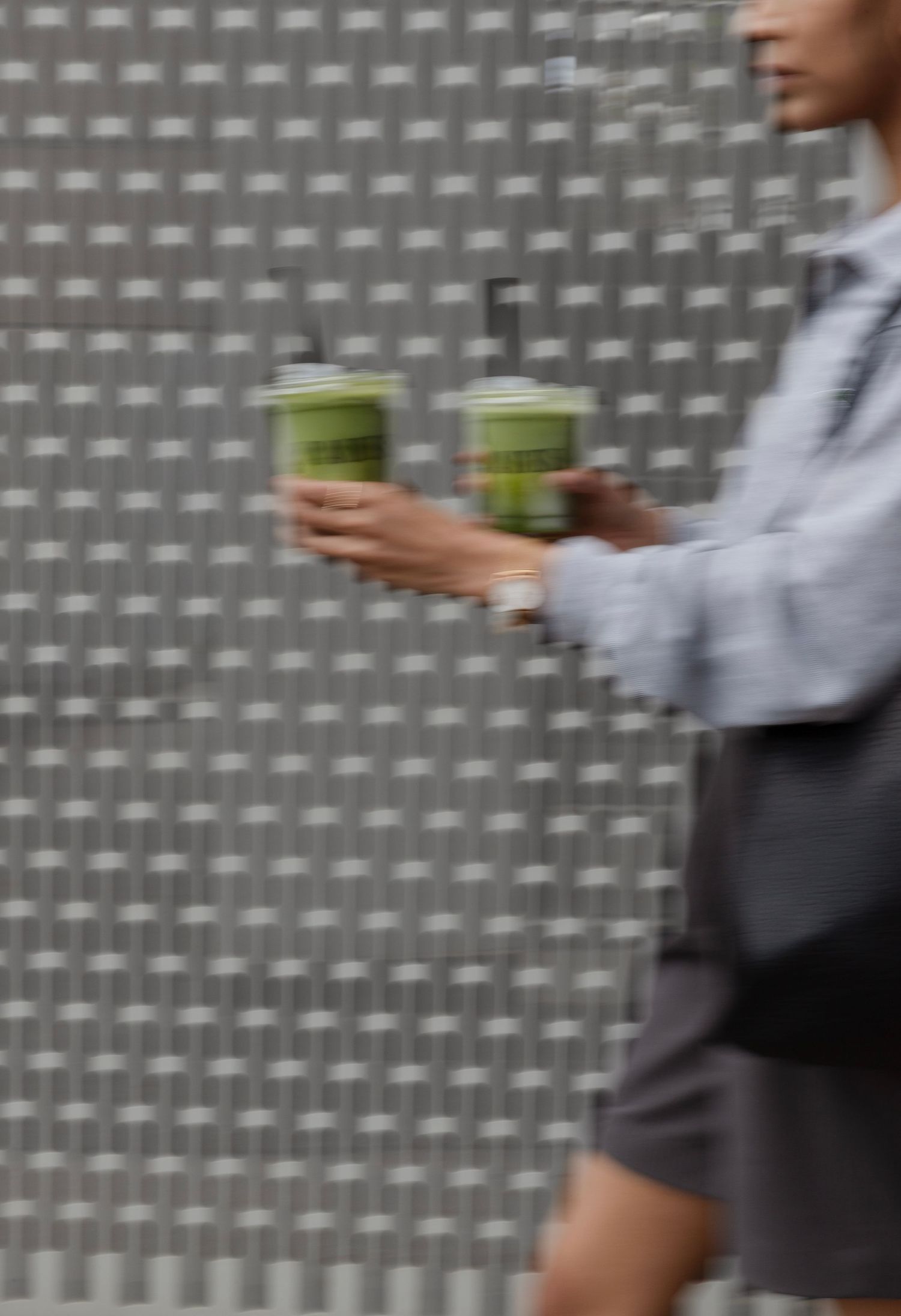 A sequence of motion showing someone in business attire walking past a grey textured wall.