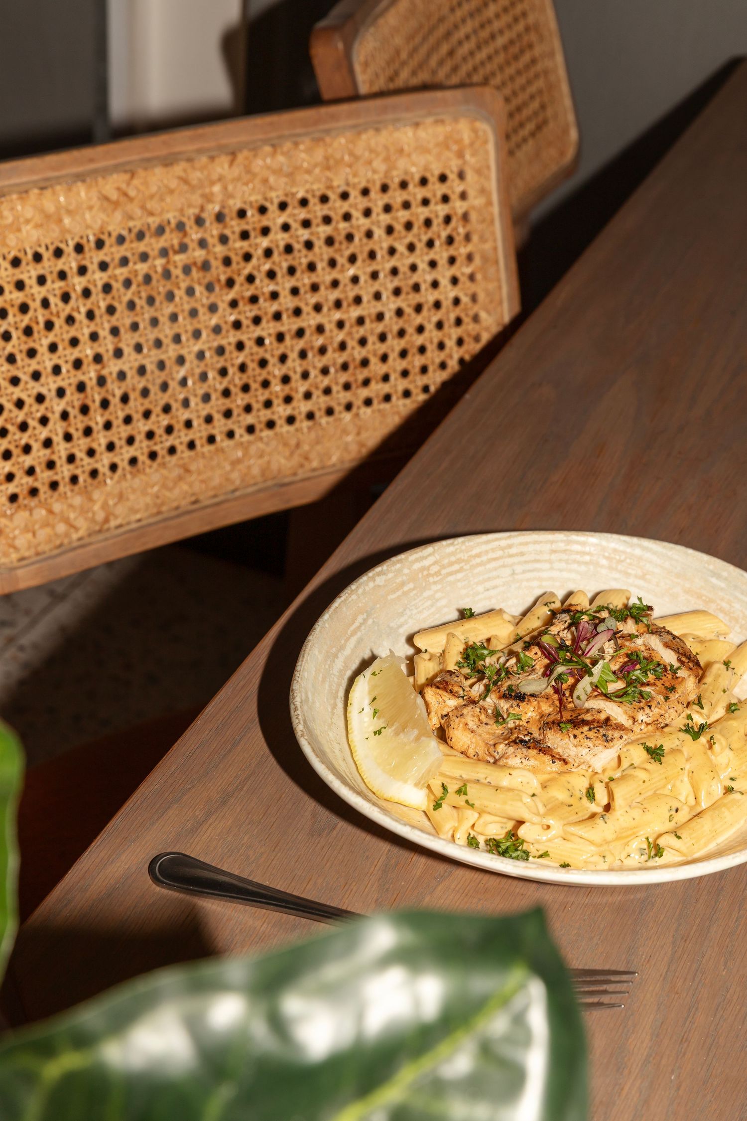 Creamy penne pasta with grilled chicken, fresh herbs, and caramelized onions served on a wooden table.