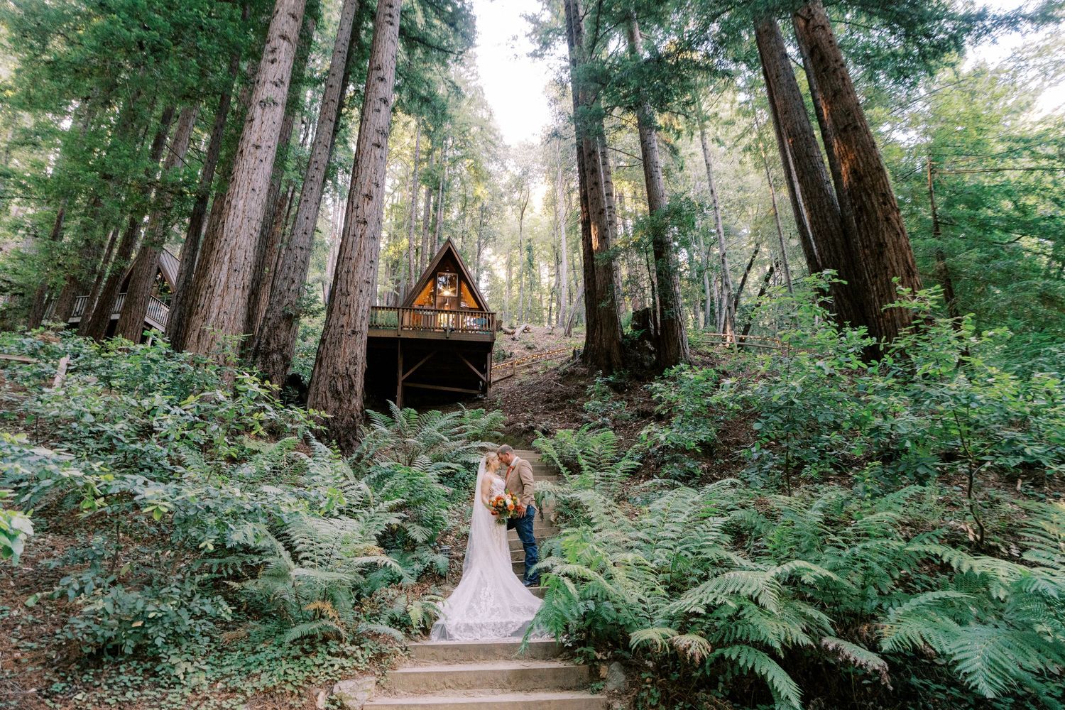 A couple shares an intimate moment on a garden path surrounded by spring blossoms and trees.