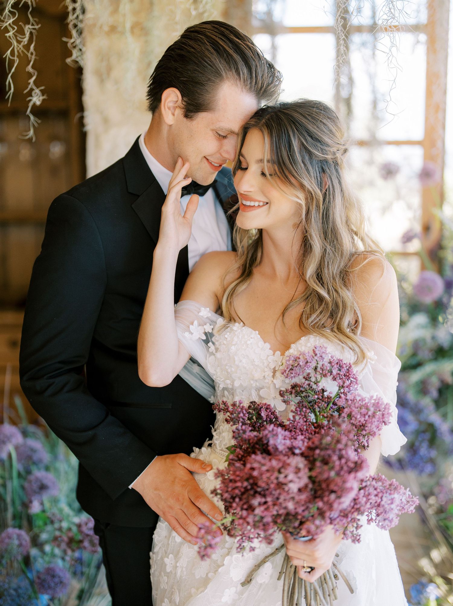 A tender wedding moment captured as a couple shares an intimate pose with a flowing veil in golden light.