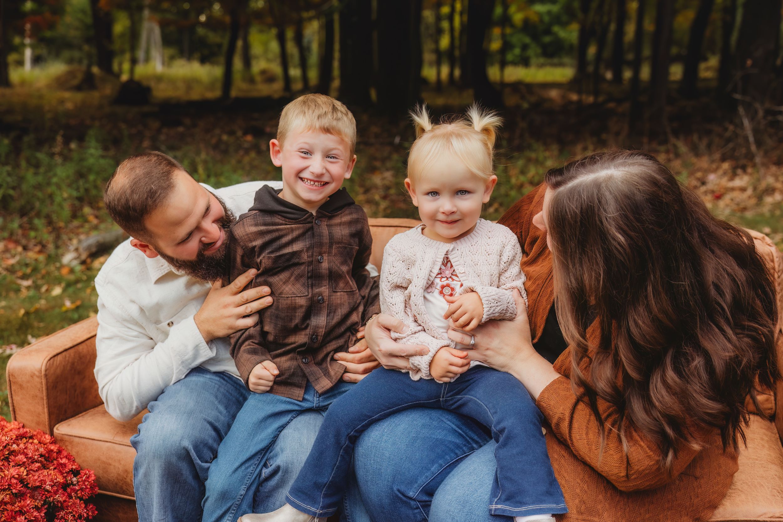 A family shares tender moments together during an outdoor autumn photoshoot in a park setting.