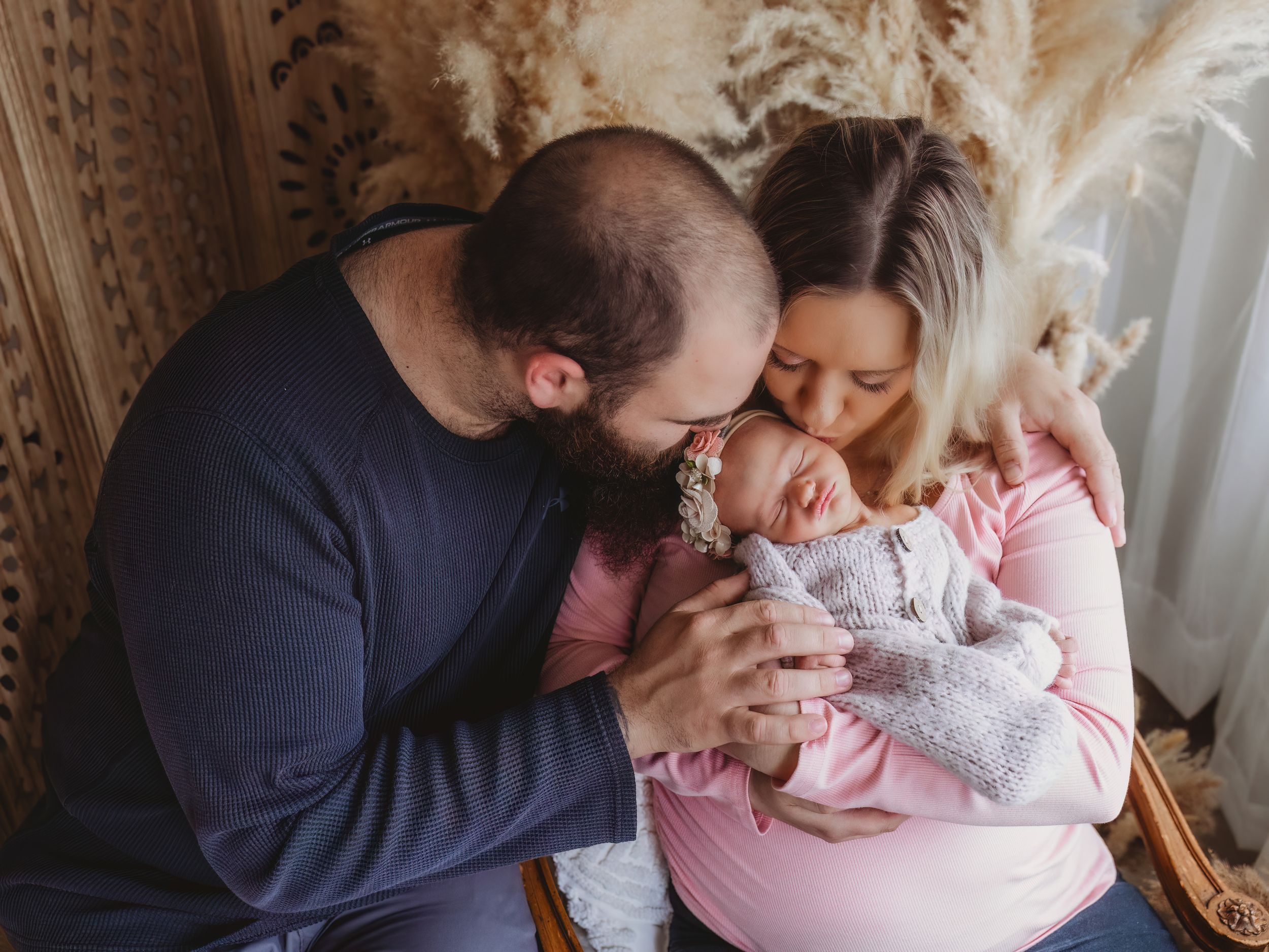 New parents lovingly gaze at their newborn baby during a professional family portrait photography session.