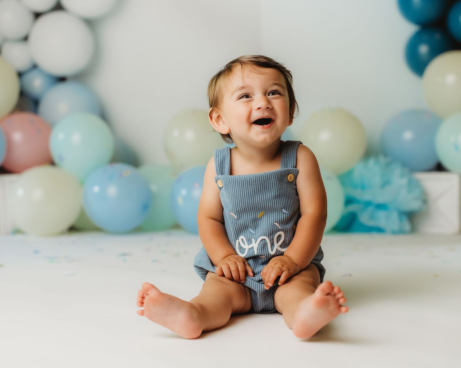 One-year-old boy enjoying his first birthday cake smash in a Central Maine studio.