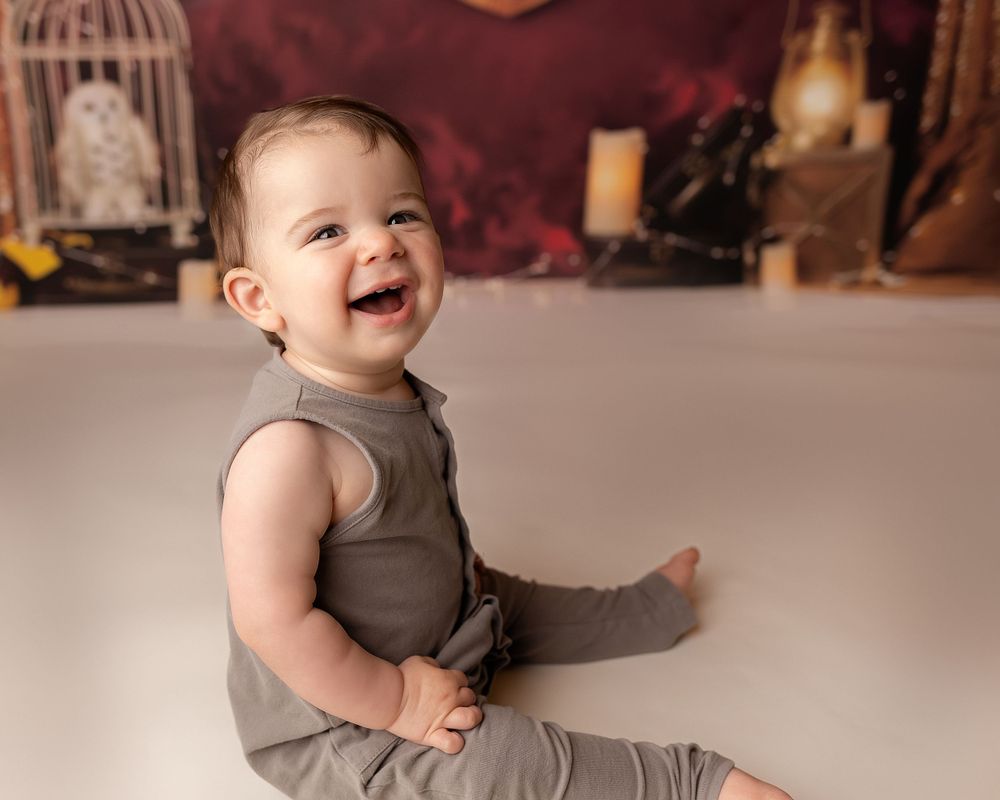 Professional photo of a toddler in brown in front of a Harry Potter themed back drop