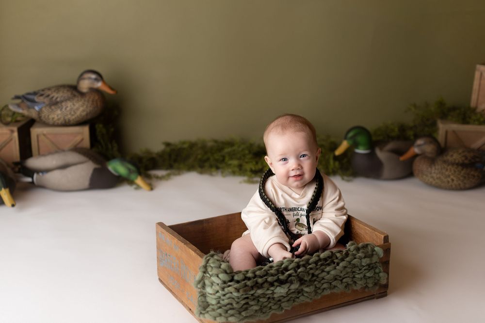 little boy for a studio 1/2 birthday session celebrating being 6 months old with duck decoys and duck calls
