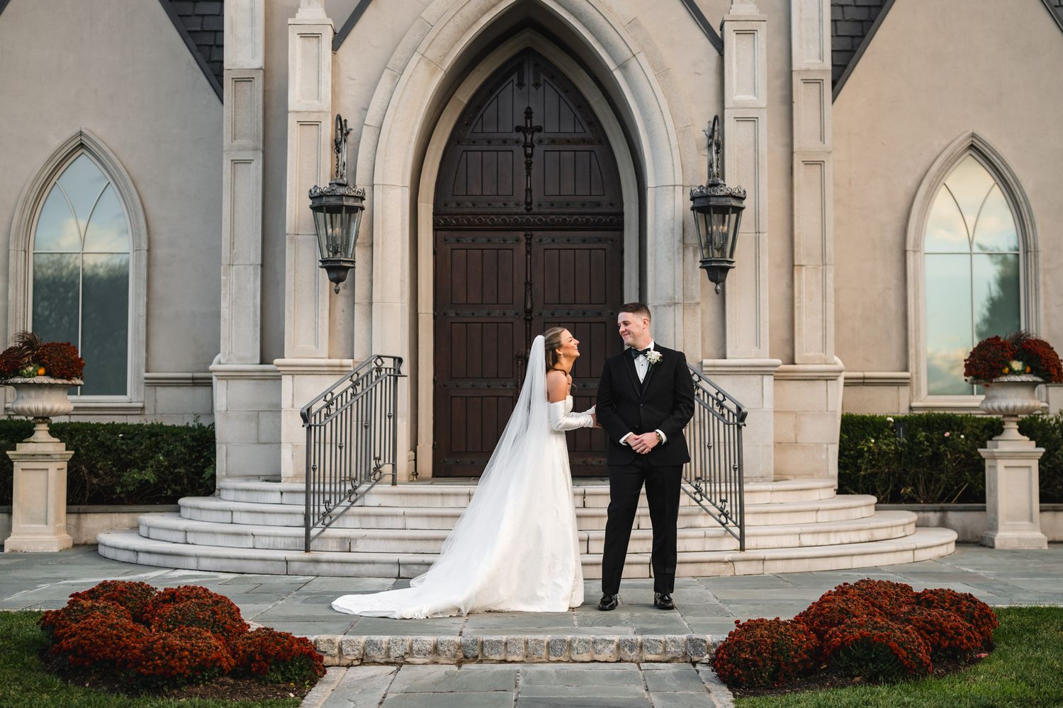 A wedding couple first look in front of an elegant stone chapel with beautiful elegant architecture and ornamental landscaping. Park Chateau