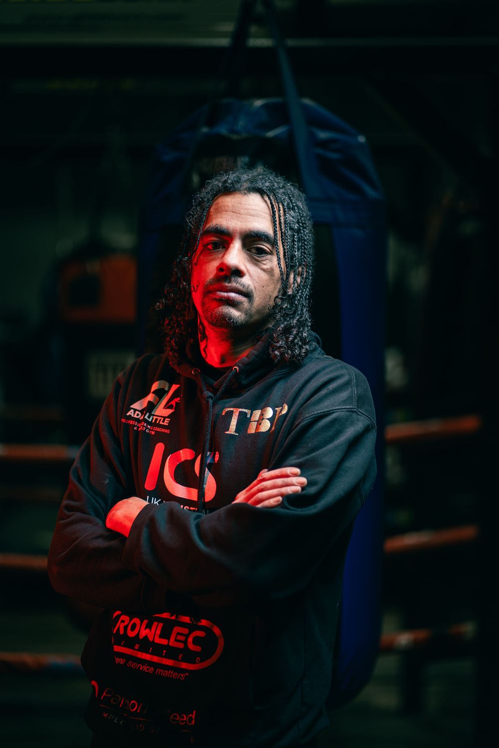 Dramatic portrait with red lighting against a dark background showing movement and shadows.