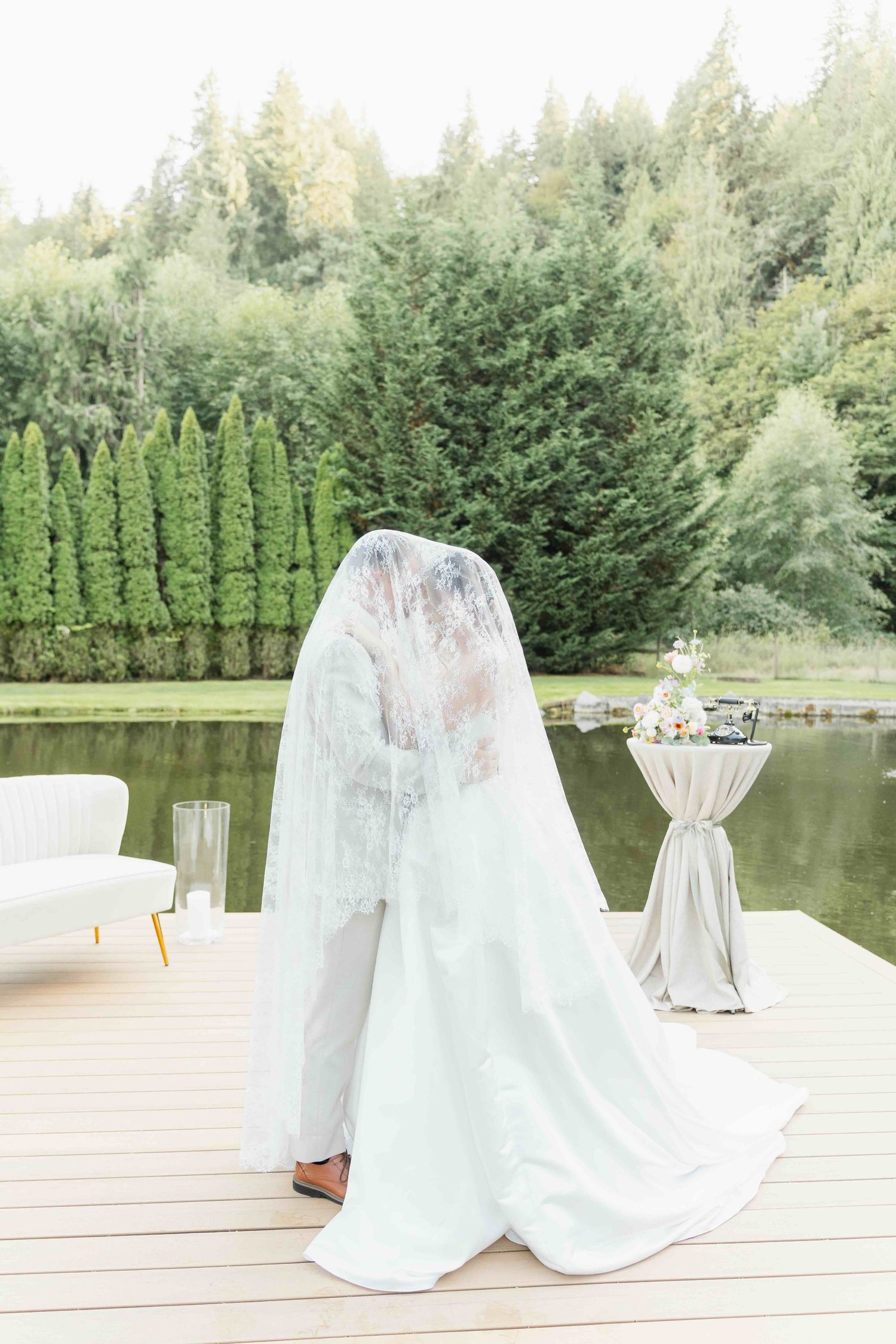 A couple holds hands on a rural dirt road while dressed in a white wedding gown and navy suit on their special day.