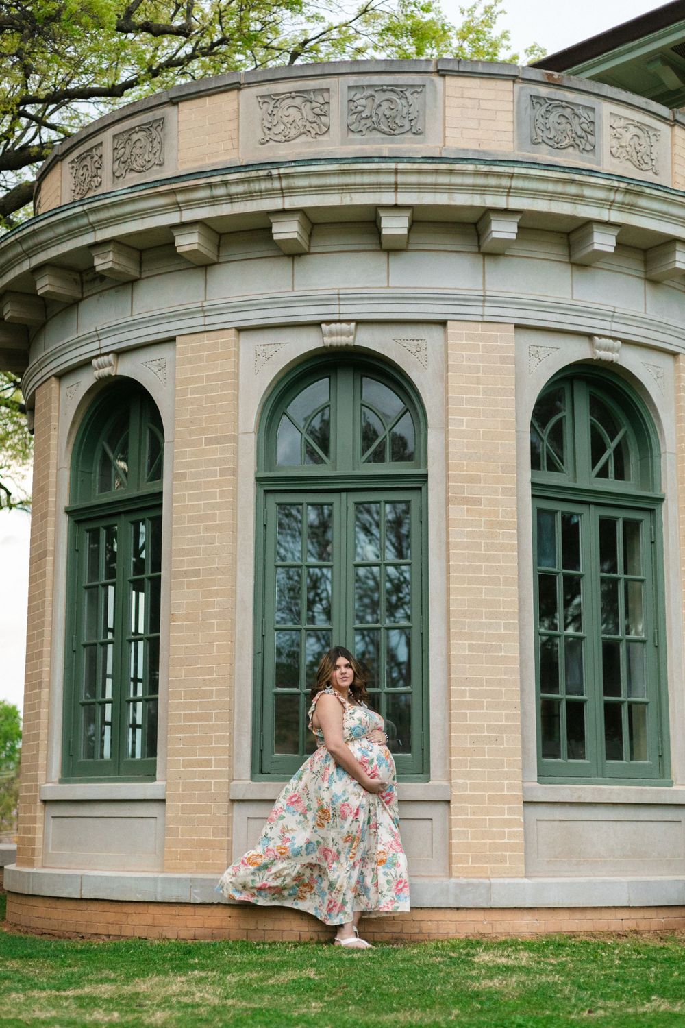 A floral dress catches the breeze against classic architectural details of a curved stone gazebo.