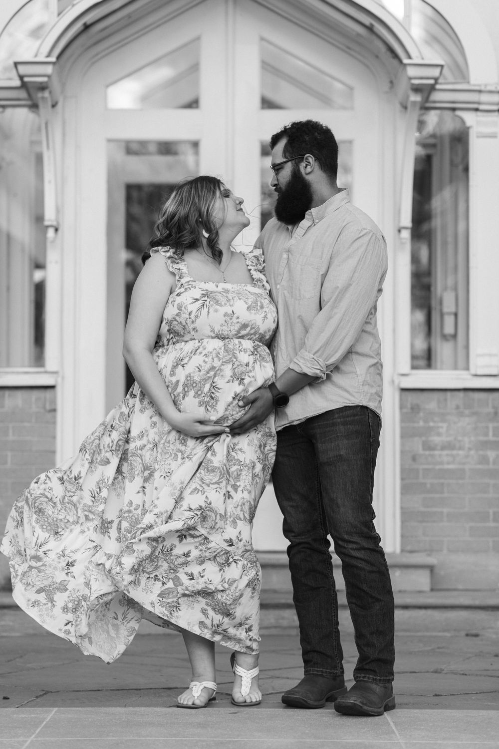 Romantic black and white portrait of couple posed in front of architectural doorway.