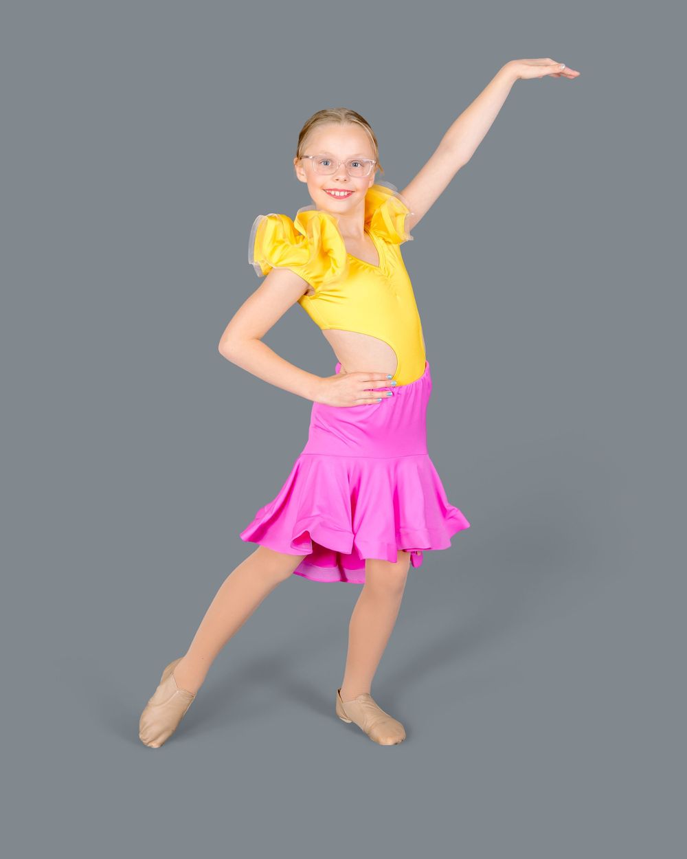 A dancer in a yellow top and pink skirt performs a series of expressive dance moves against a gray backdrop.