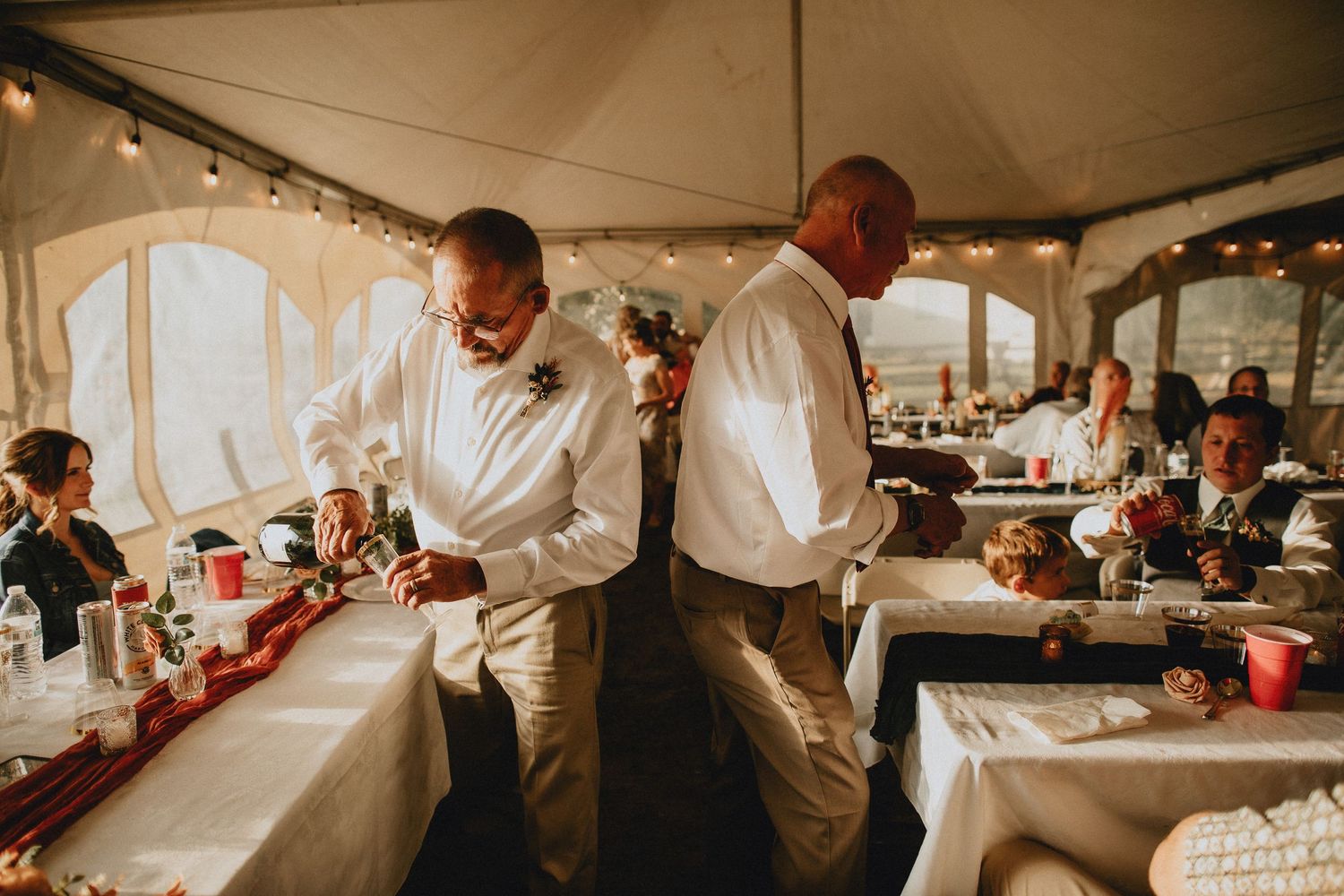 Fathers of the bride and groom pouring champagne, getting ready for toasts.