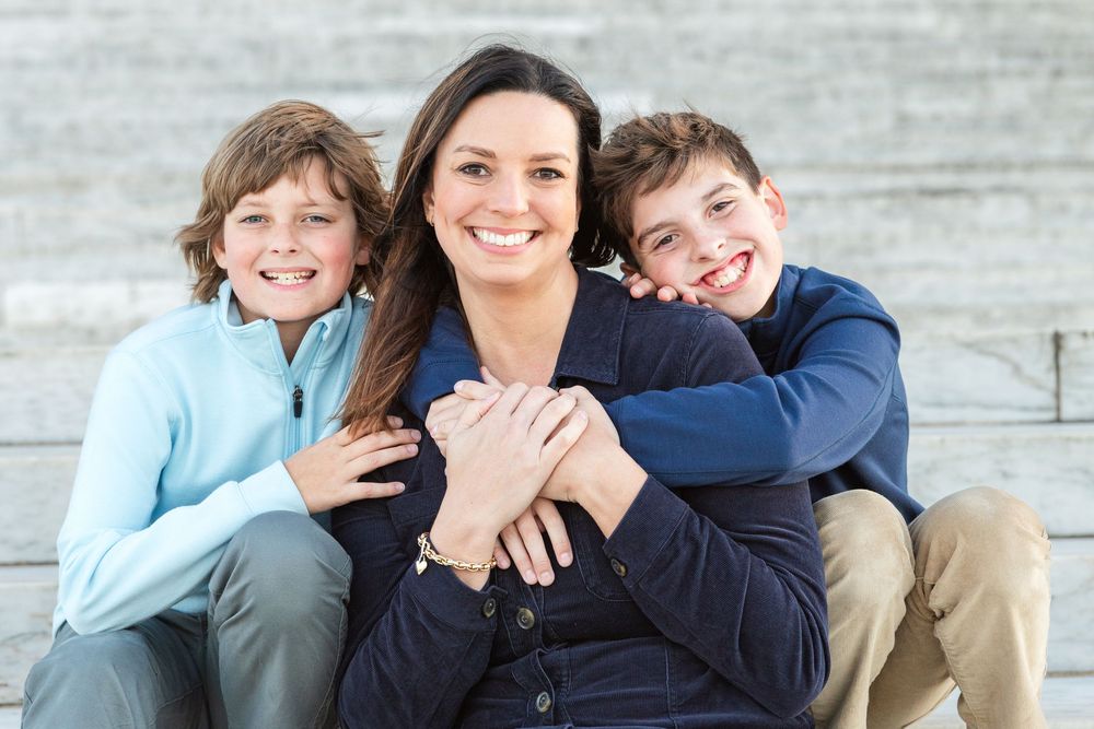 A family sits together on outdoor steps, sharing warm embraces and joyful laughter in a casual photo session.