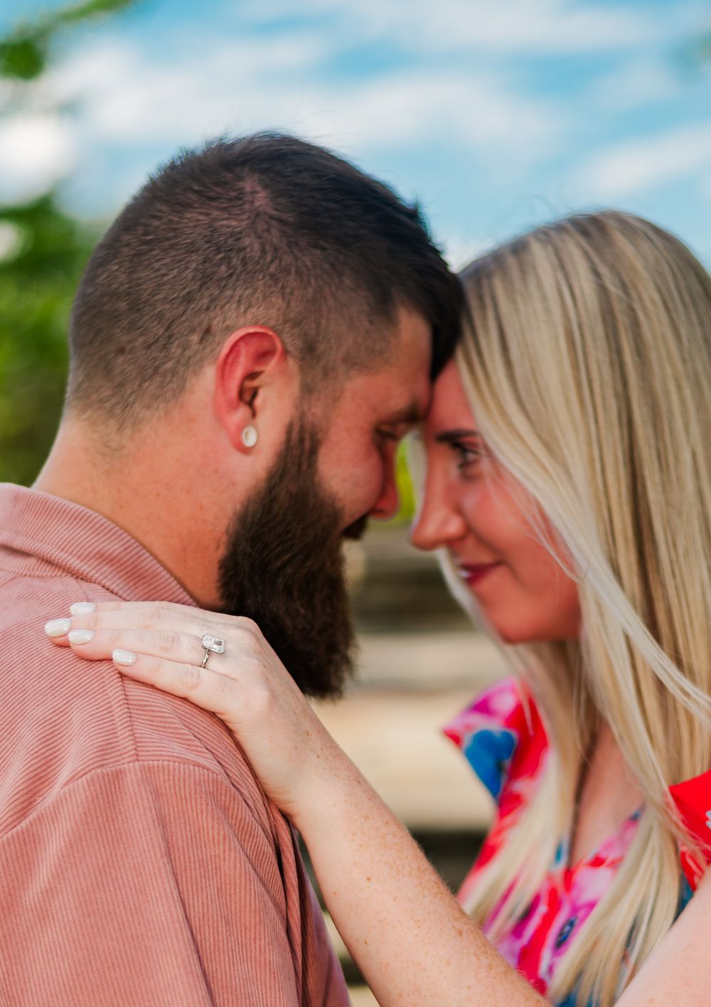 An intimate moment between a couple with the woman's hand resting on her partner's bearded face.