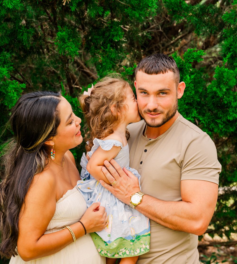 Happy family moment captured outdoors with natural greenery backdrop.