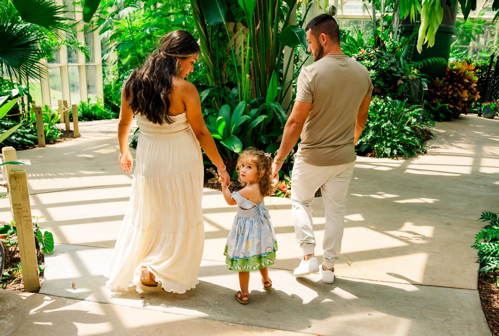 Family walking together in sunlit tropical garden setting.