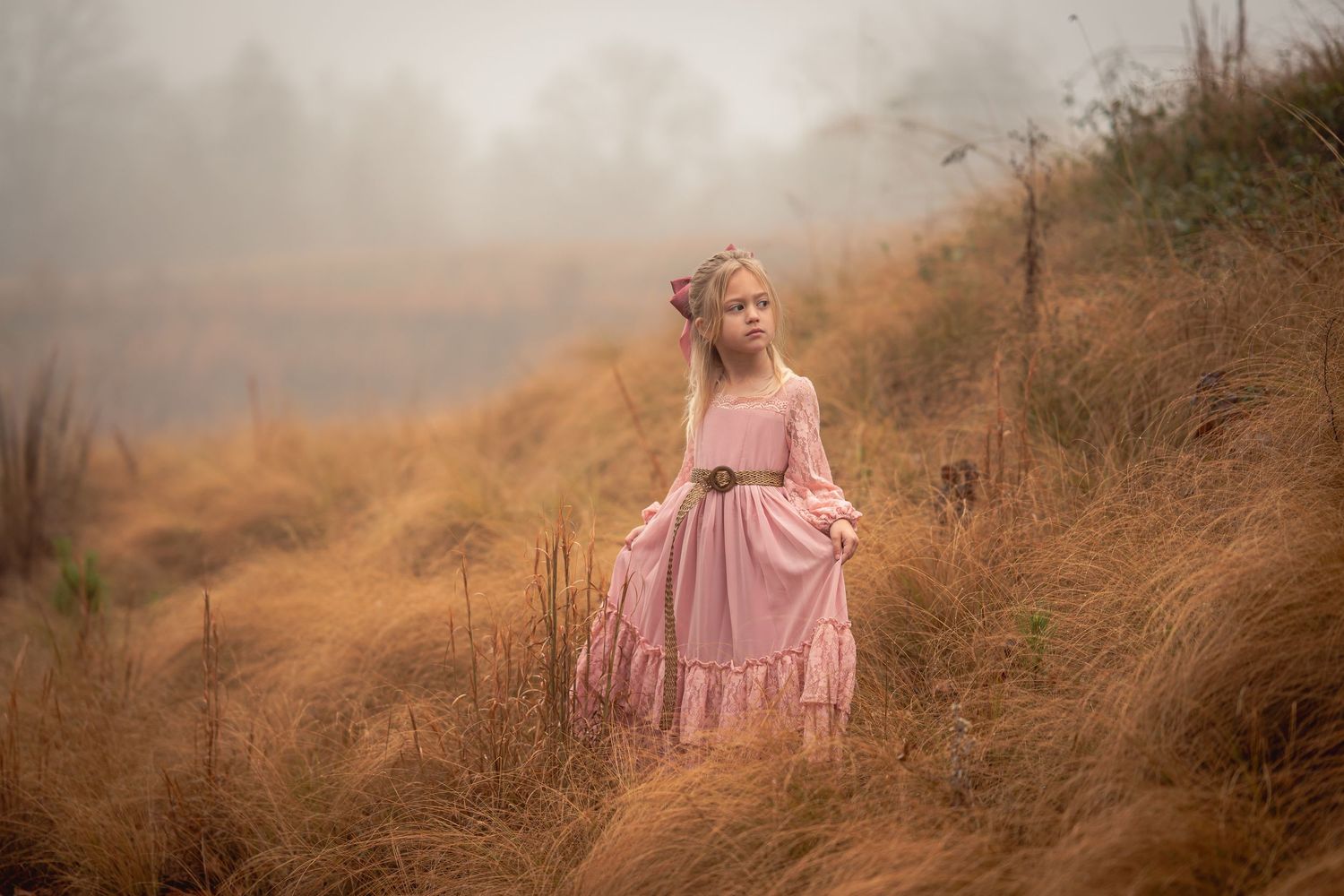 A small dancer in a pink tulle dress twirls barefoot on a wooden bridge surrounded by autumn foliage.