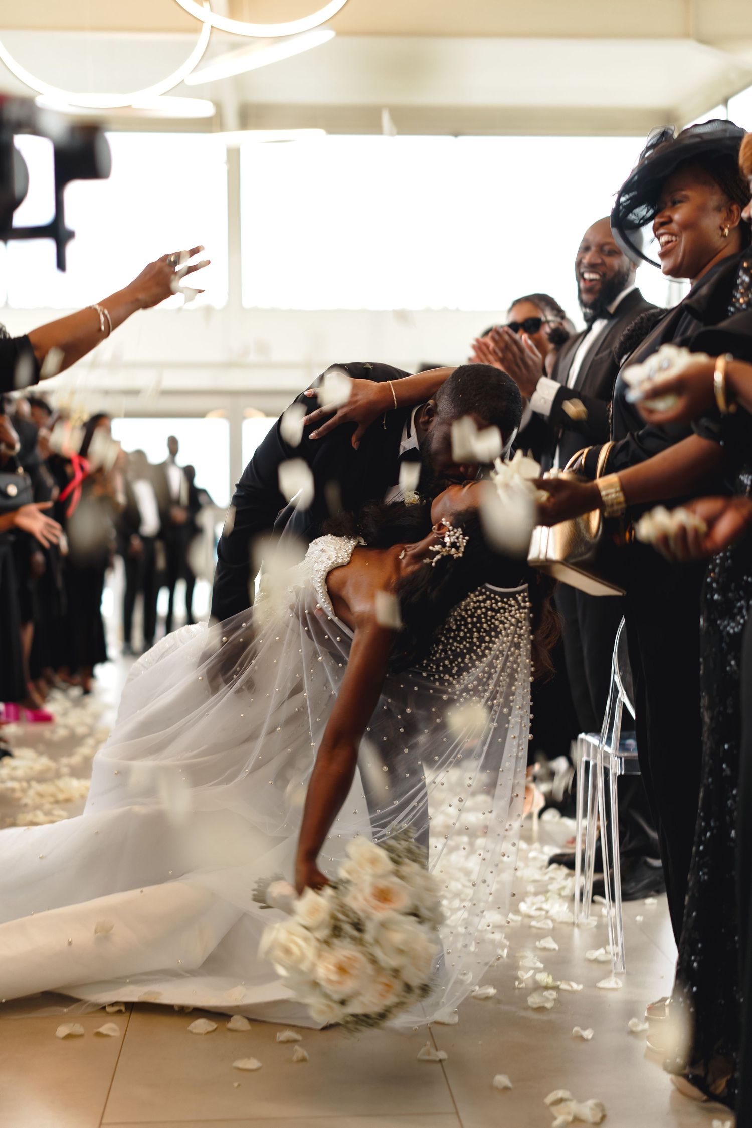 Wedding party gathered on outdoor steps with bride in flowing white gown.