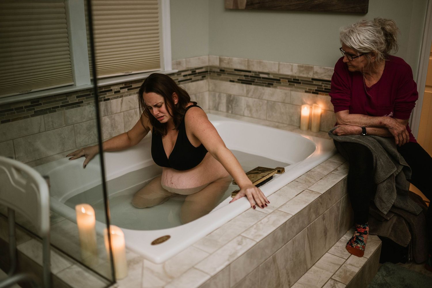 Candlelit bath scene with person relaxing in marble tub.