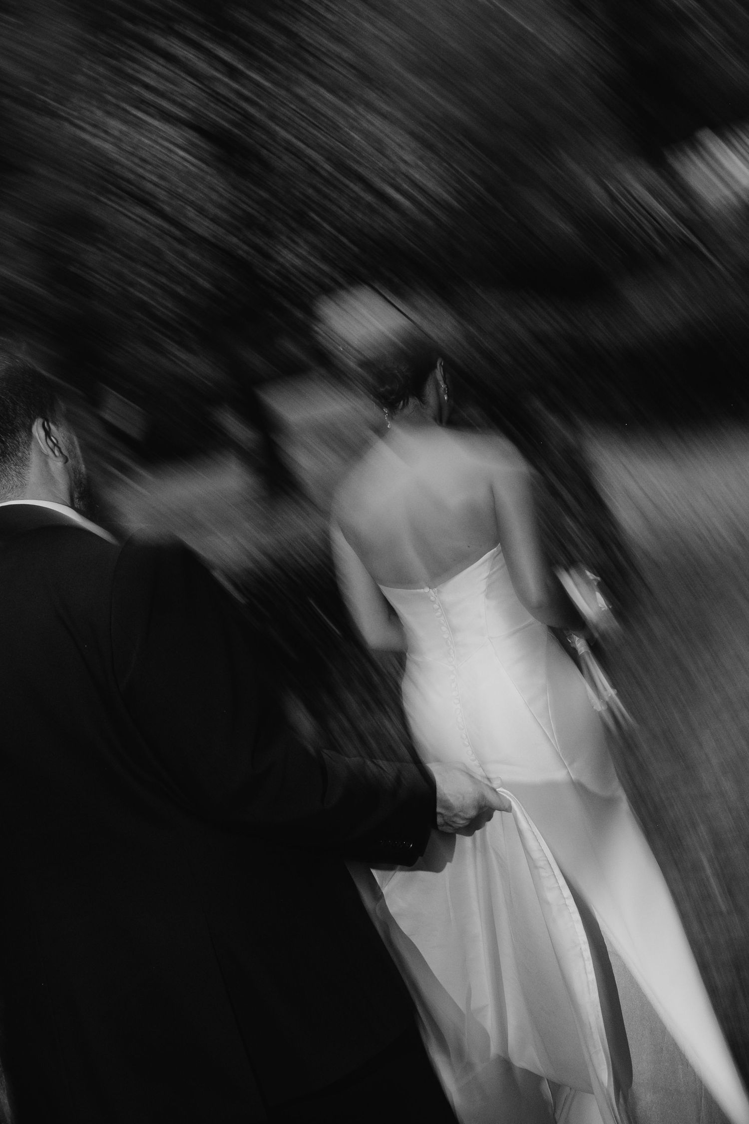 Fotografia abstrata de casamento em preto e branco com efeito de movimento e contrastes de luz sobre fundo escuro.