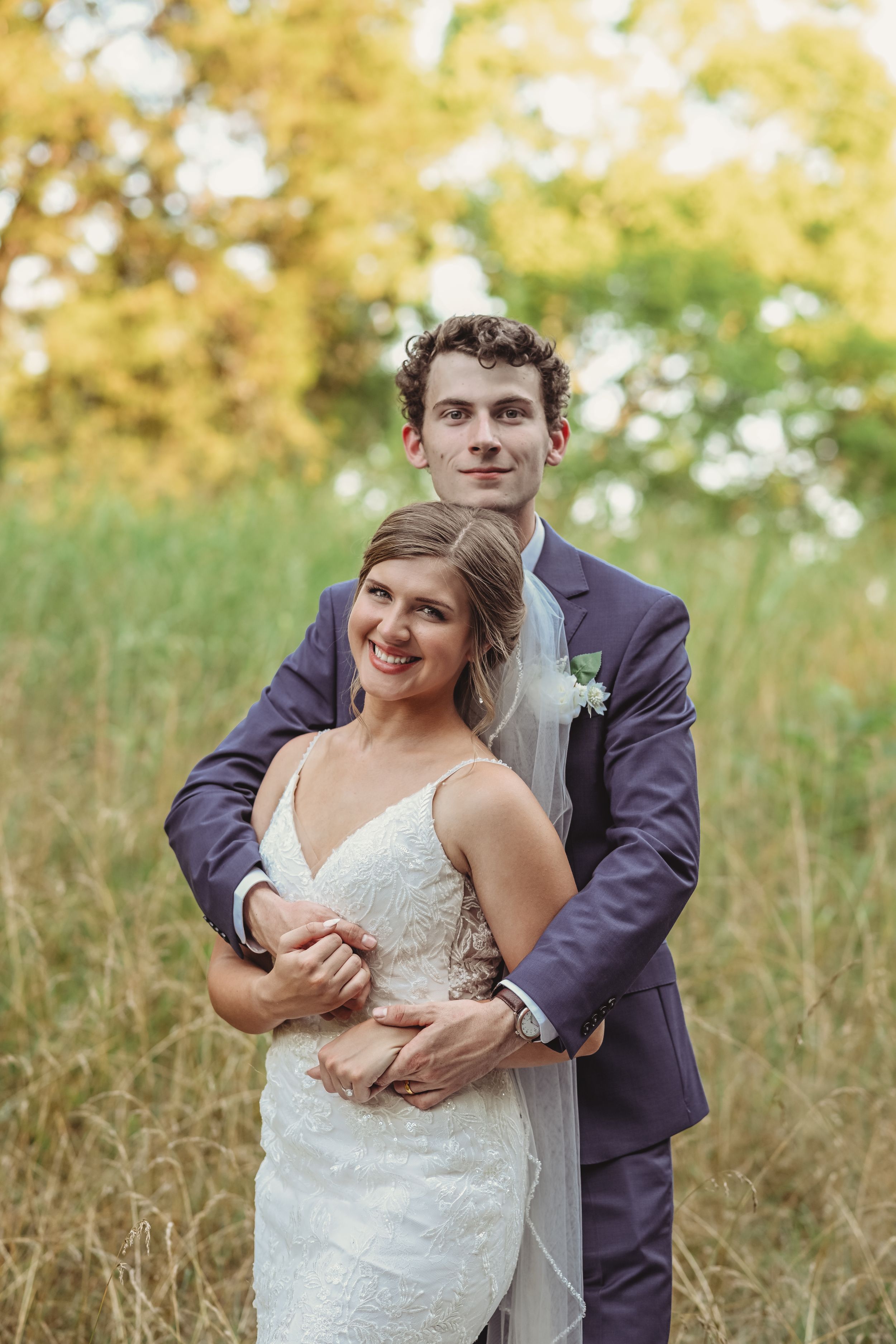 Couple shares playful moment in golden field during wedding photo session.