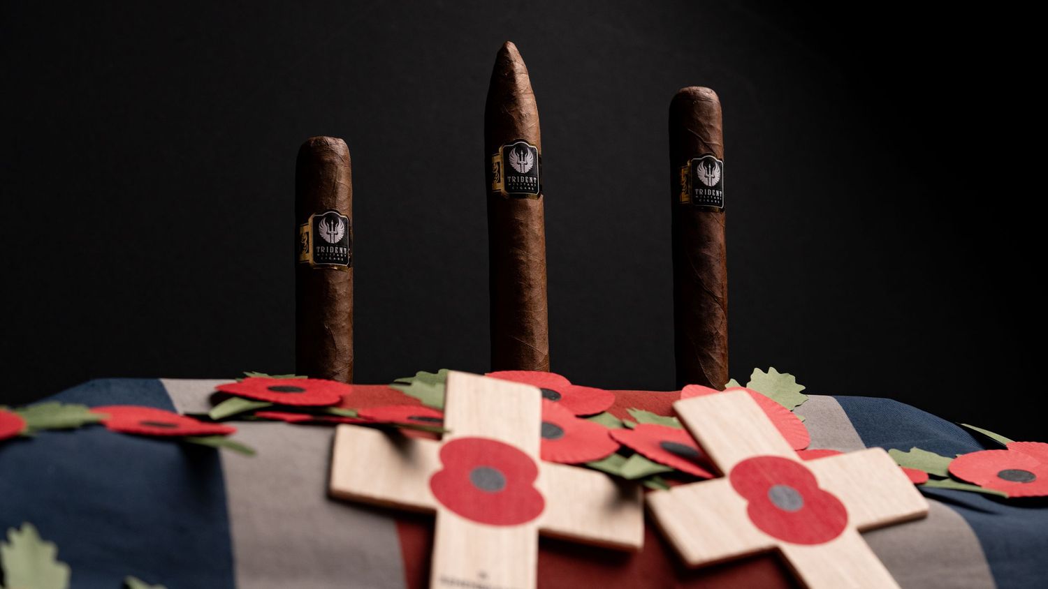 Three cigars arranged vertically on a flag with red poppies.