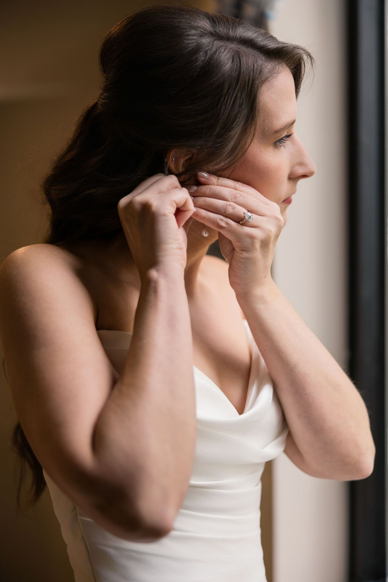 Close-up sequence of putting on earrings against bright window light. Columbus Ohio Wedding