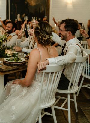 Guests raise champagne glasses in a toast during an elegant rustic wedding reception at wooden tables with white chairs-Northridge Inn