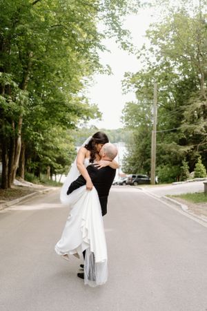 A couple shares a romantic embrace on a tree-lined street at Windermere House In Muskoka-Alexis Anne Photography
