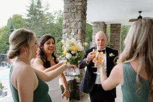A group socializes and shares drinks on a stone porch during an wedding celebration at Windermere House in Muskok- Alexis Anne Photography