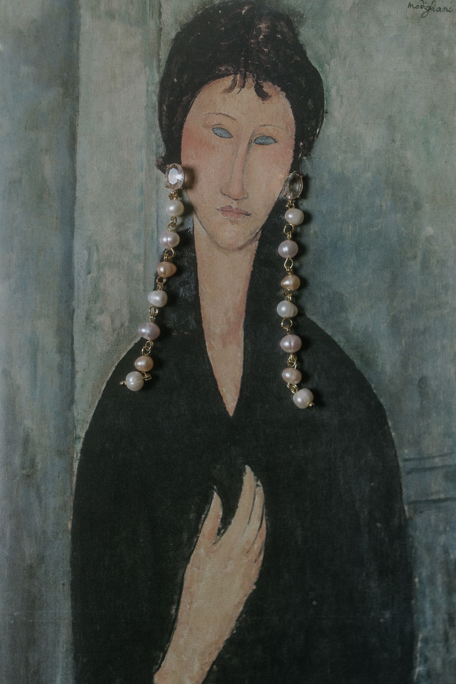 Modigliani-style portrait painting of a figure with dark hair wearing pearl earrings and a black garment against gray wall.