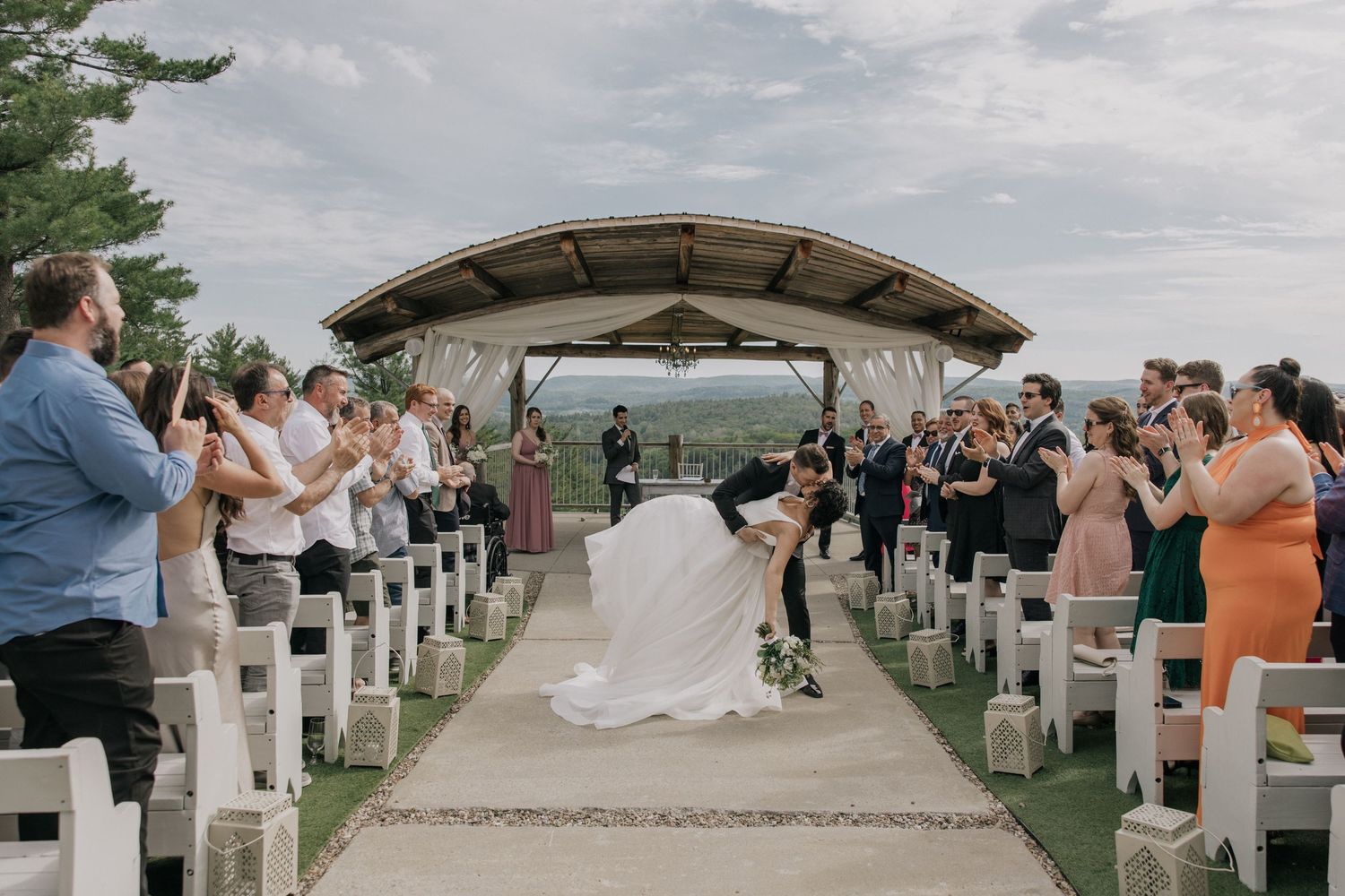 Wedding ceremony on a scenic mountain overlook with white chairs and natural landscape views.