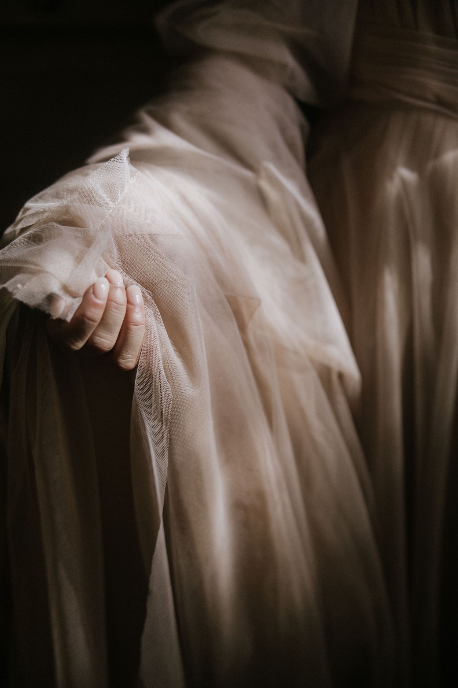 Abstract motion blur of delicate white tulle fabric creating an ethereal flowing effect in sepia tones.