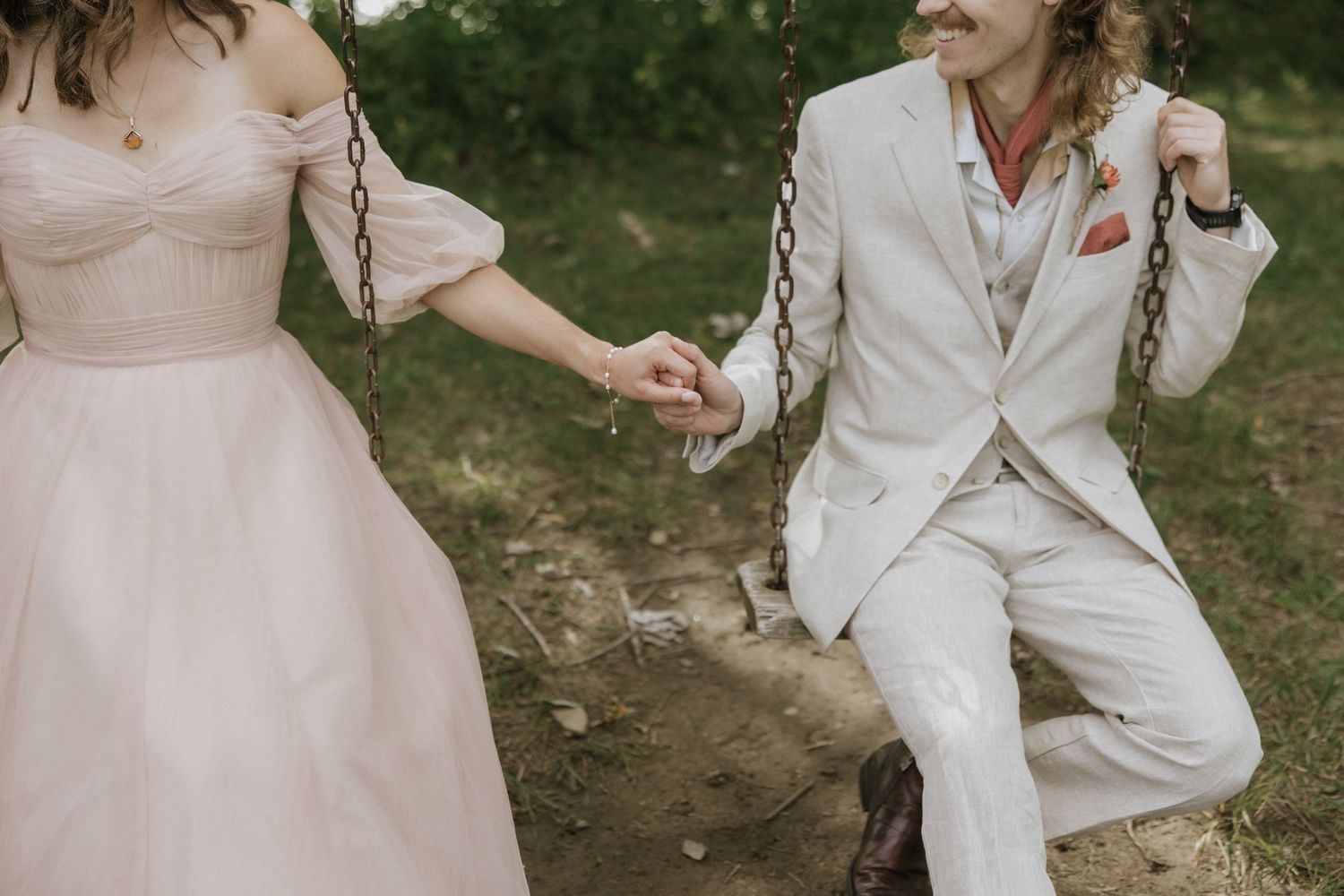 A couple in wedding attire dances together in a rustic outdoor setting during their celebration.