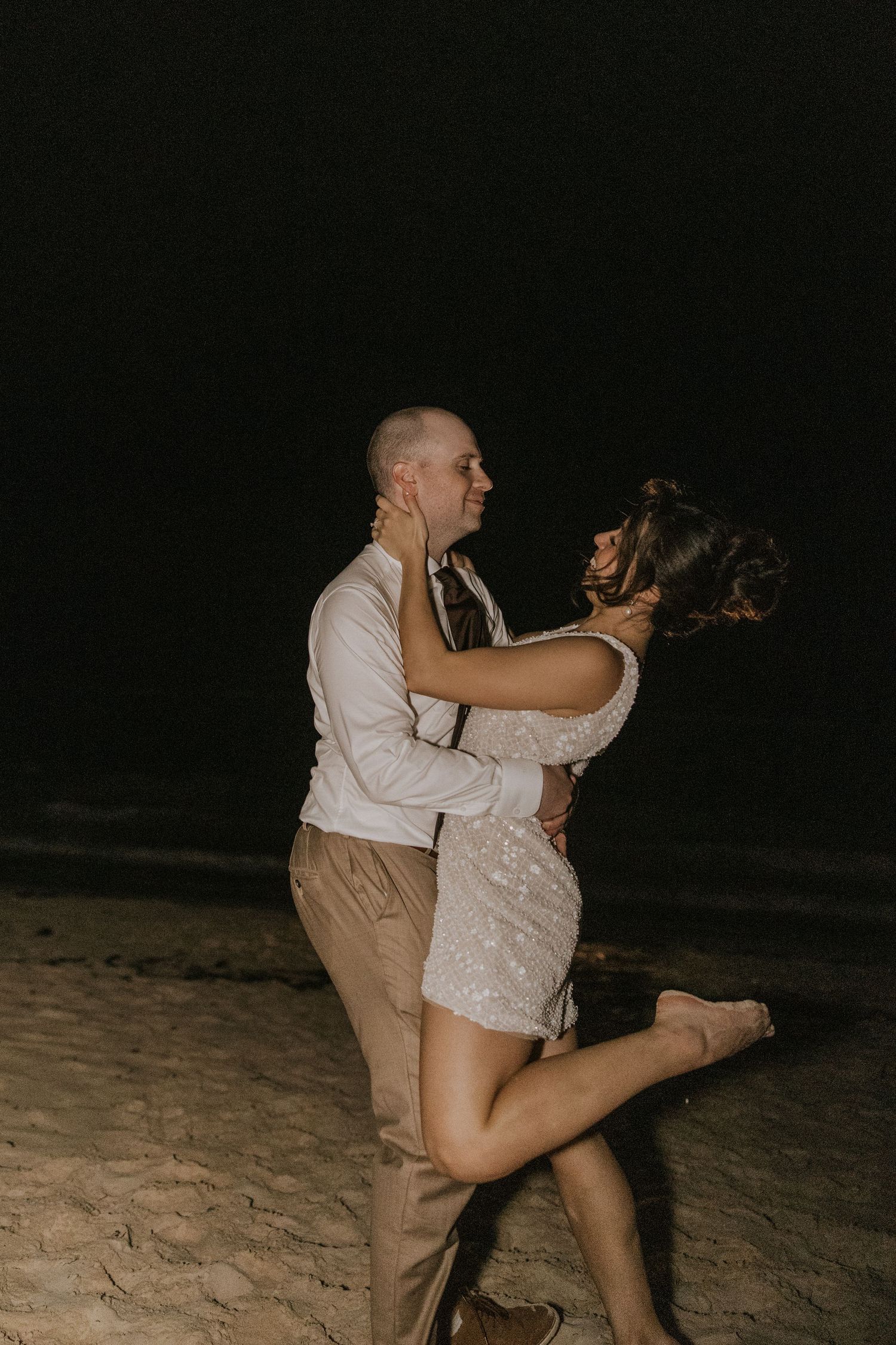 A couple dances together on the beach at night, captured in a sequence of romantic movement shots.