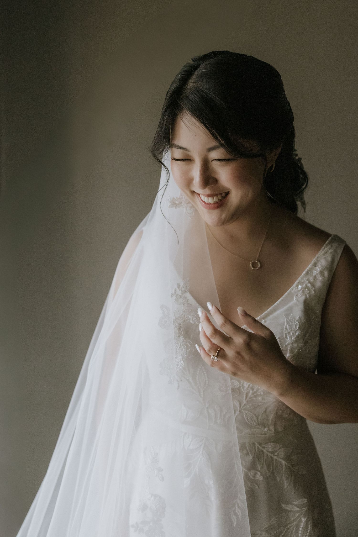A series of moody bridal portraits showing details of white lace wedding dress and flowing veil in natural light.