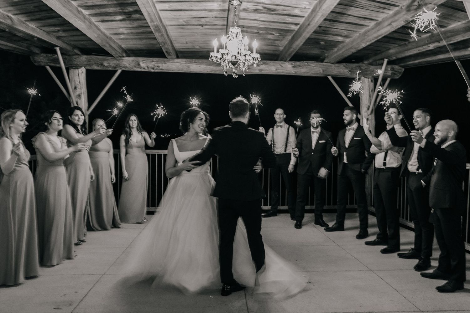 Indoor wedding reception with chandelier and guests lining the dance floor.