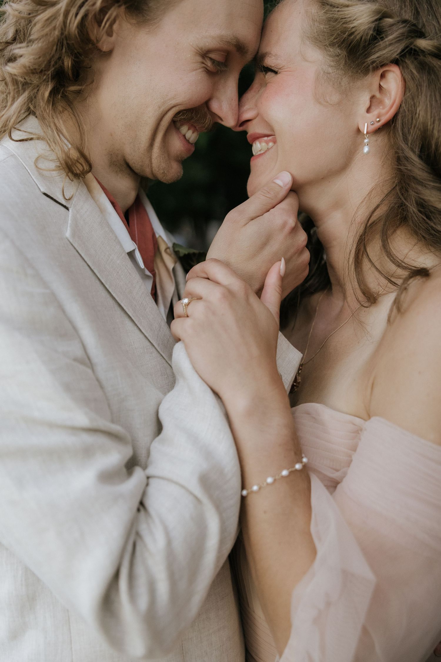 A romantic close-up moment between a couple in wedding attire sharing an intimate laugh together.