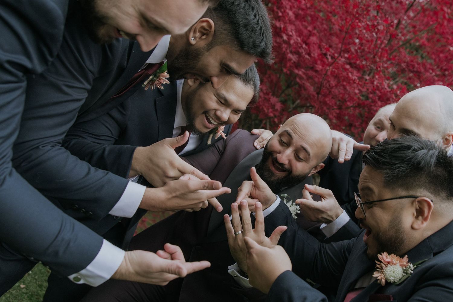 A group of friends share a laugh while looking at something on their mobile phones at an outdoor gathering.